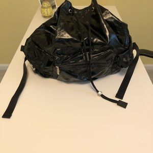 A large black shiny Sportsac backpack with many pockets/zippers inside and out.